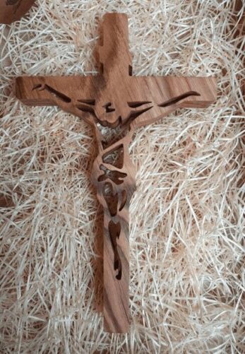 krzyż z wyciętym wizerunkiem jezusa chrystusa wykonany z drewna, fotografowany na tle sianka