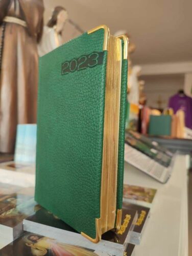 kalendarz 2023 w zielonej okładce, widoczne złote ranty kartek