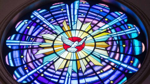symbol ducha świętego jako witraż w oknie kościelnym